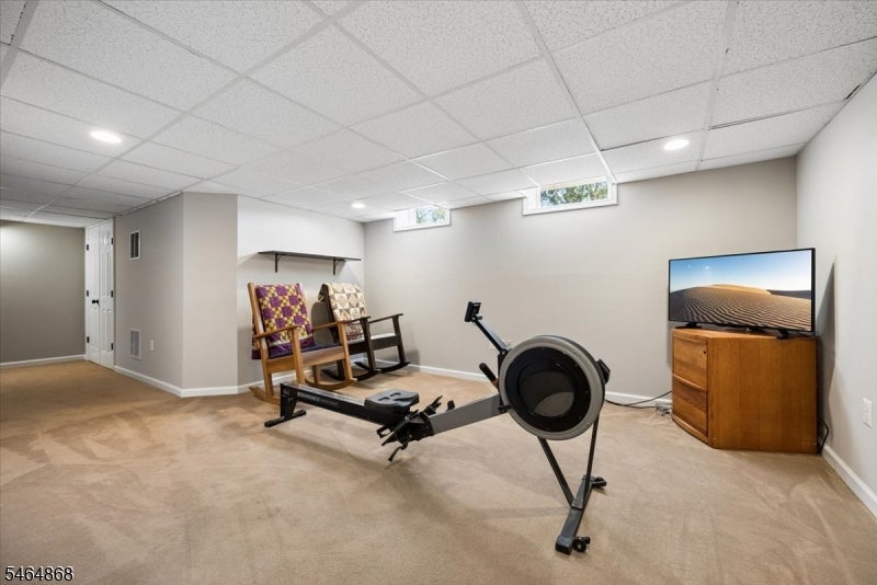 Basement exercise room with a rowing machine, rocking chairs, and a television.