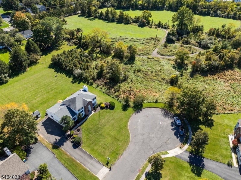 Aerial view of a white house at the end of a cul-de-sac, with broad lawns and open fields beyond.
