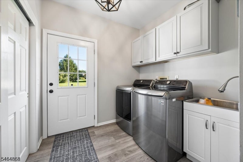 Laundry room with washer and dryer, white cabinets, utility sink, and a windowed exterior door.