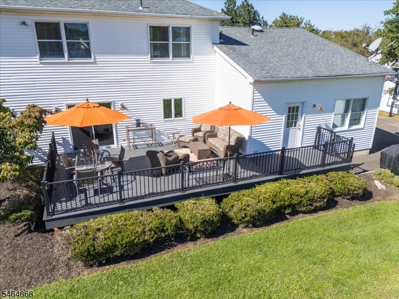 Raised deck behind a white two-story house, furnished with outdoor seating and two orange umbrellas.