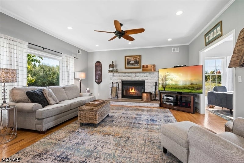 Living room with a brick fireplace, gray sectional, patterned rug, and ceiling fan.