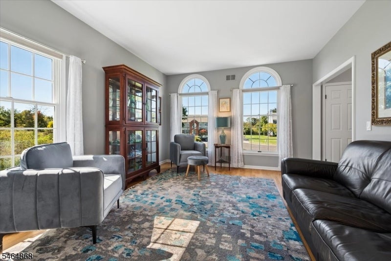 Living room with gray and black sofas, a wooden display cabinet, and tall arched windows.