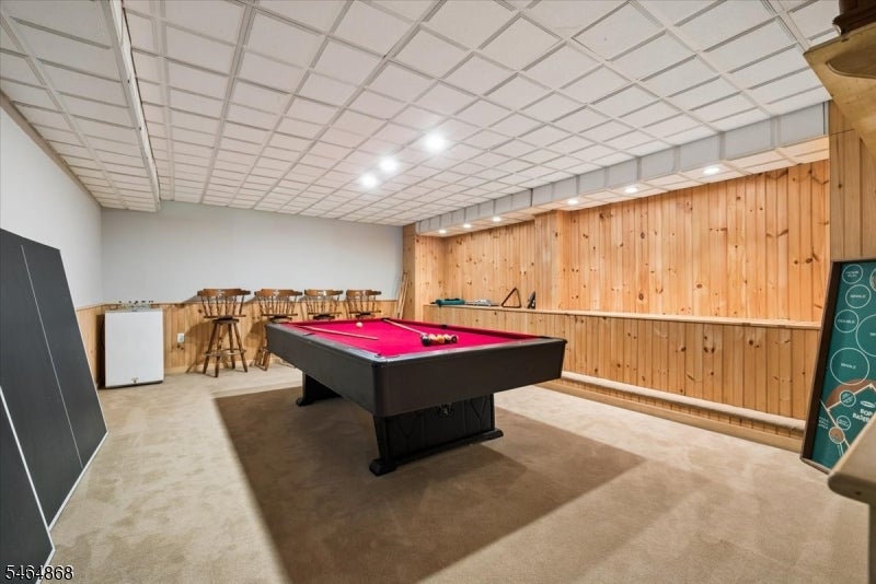 Recreation room with a red-felt pool table, wood-paneled walls, and bar stools.