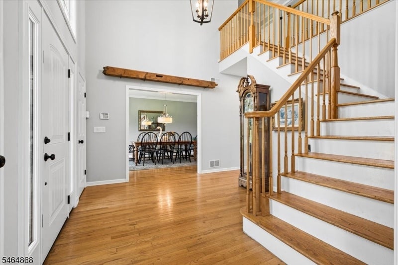 Foyer with a sweeping wooden staircase, hardwood floors, and a dining room visible through the doorway.