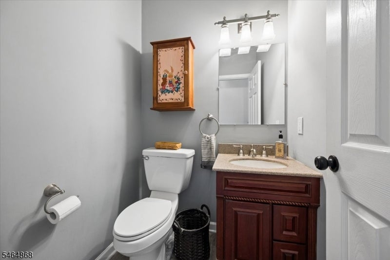 Bathroom with a dark wood vanity, oval sink, and white toilet beside an open door.