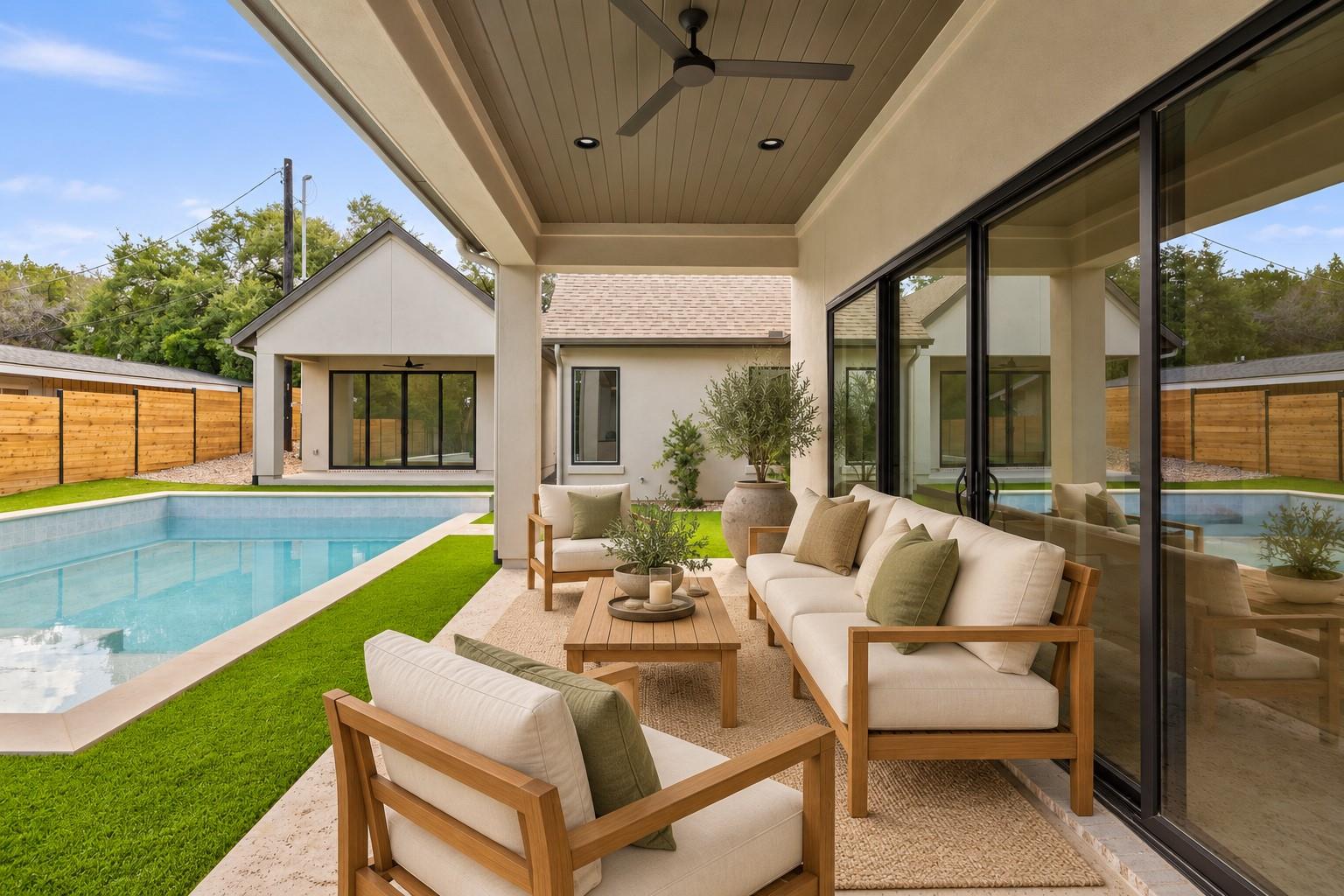 Covered patio with wood-framed lounge seating beside a swimming pool and modern glass doors.