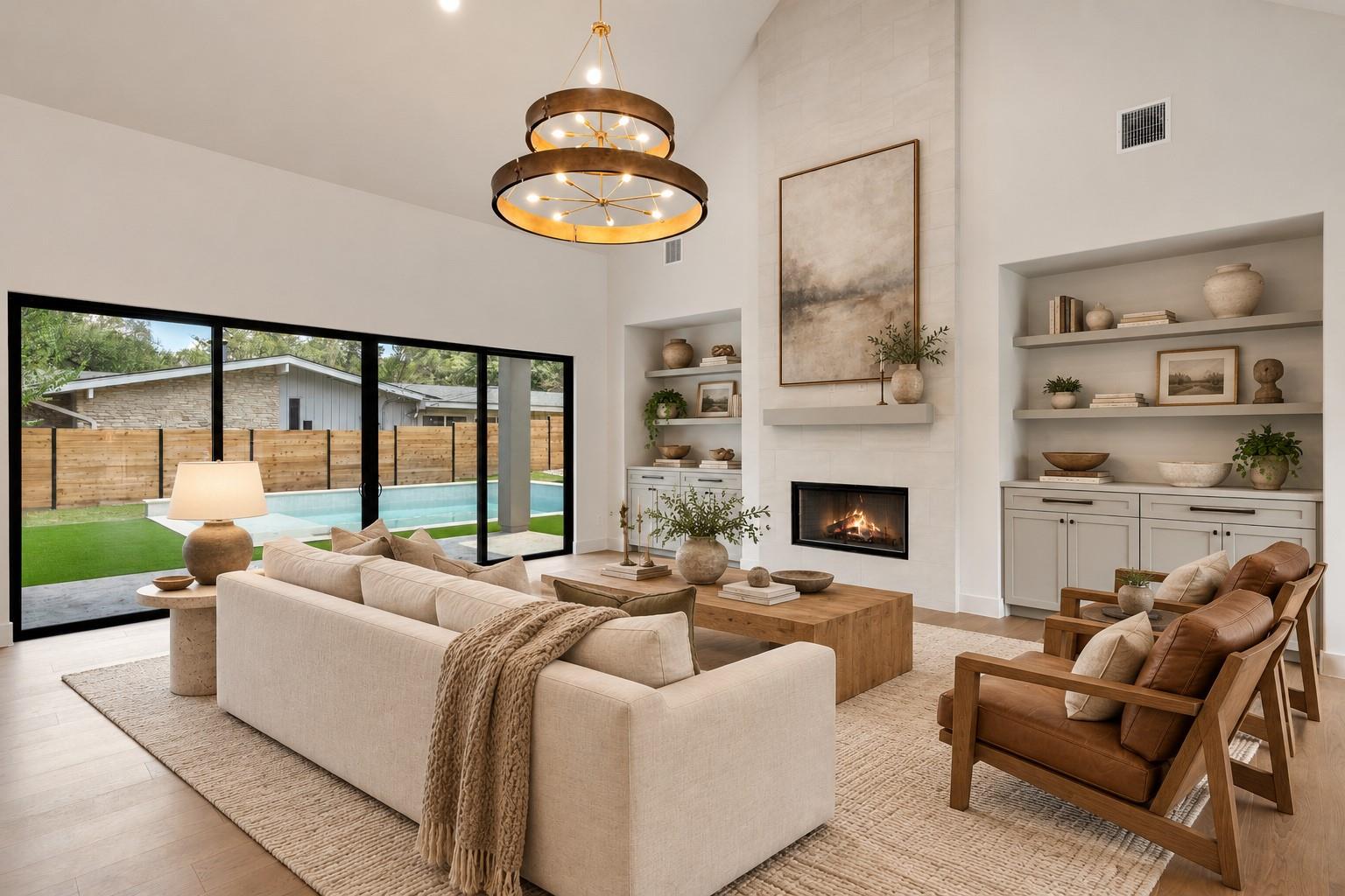 Living room with a tall fireplace, cream sofa, and sliding doors overlooking a backyard pool.