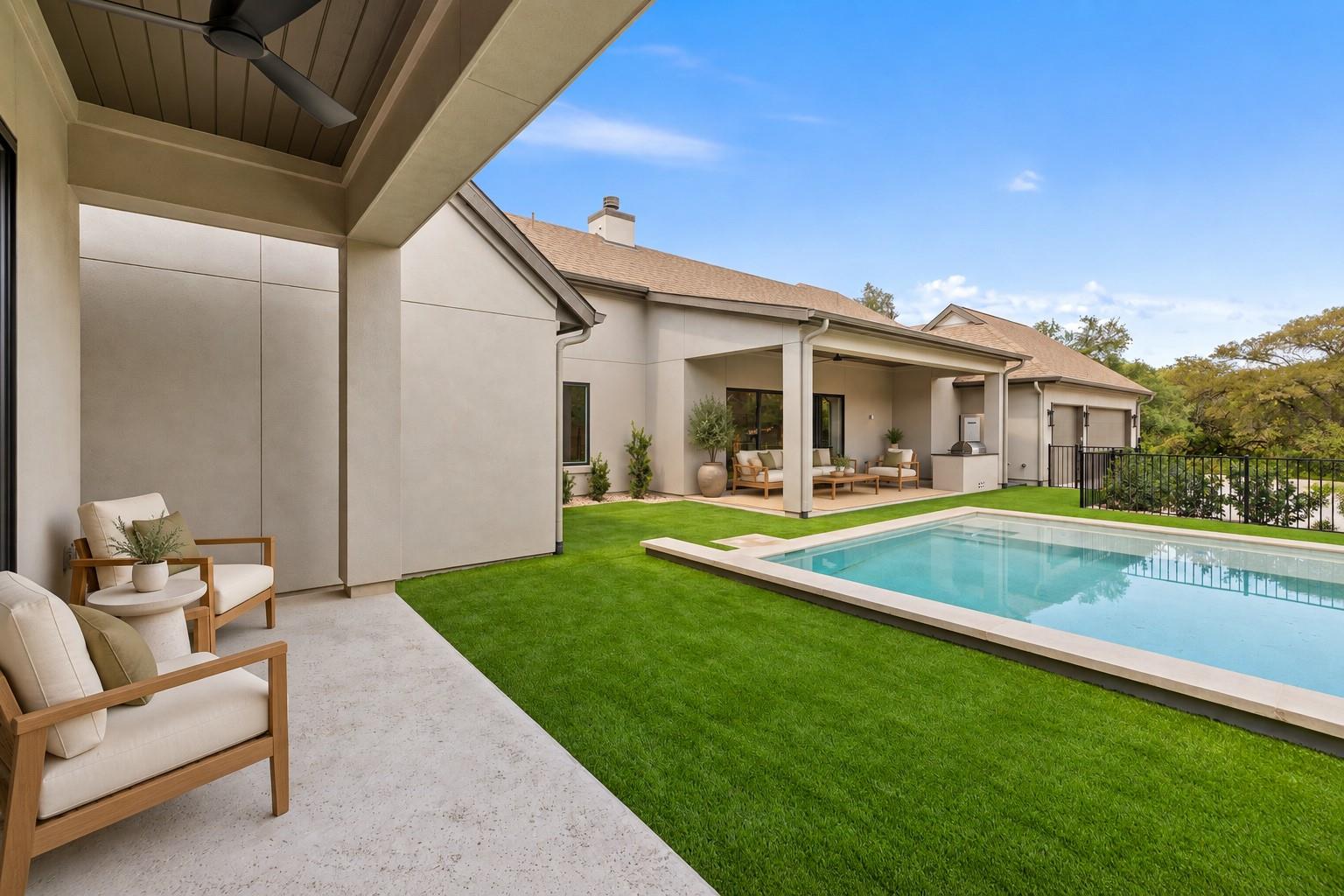 Modern home’s covered backyard patio and swimming pool beside a neatly manicured lawn.
