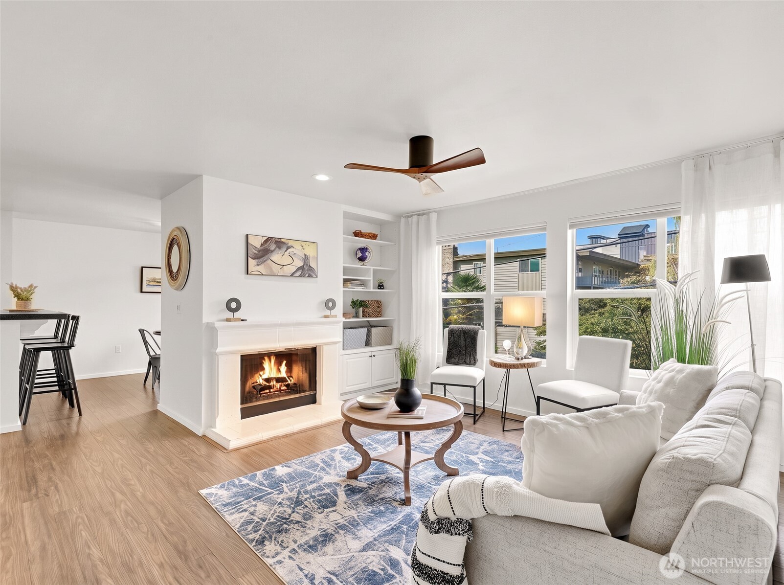 Bright living room with a white fireplace, built-in shelves, and large windows.