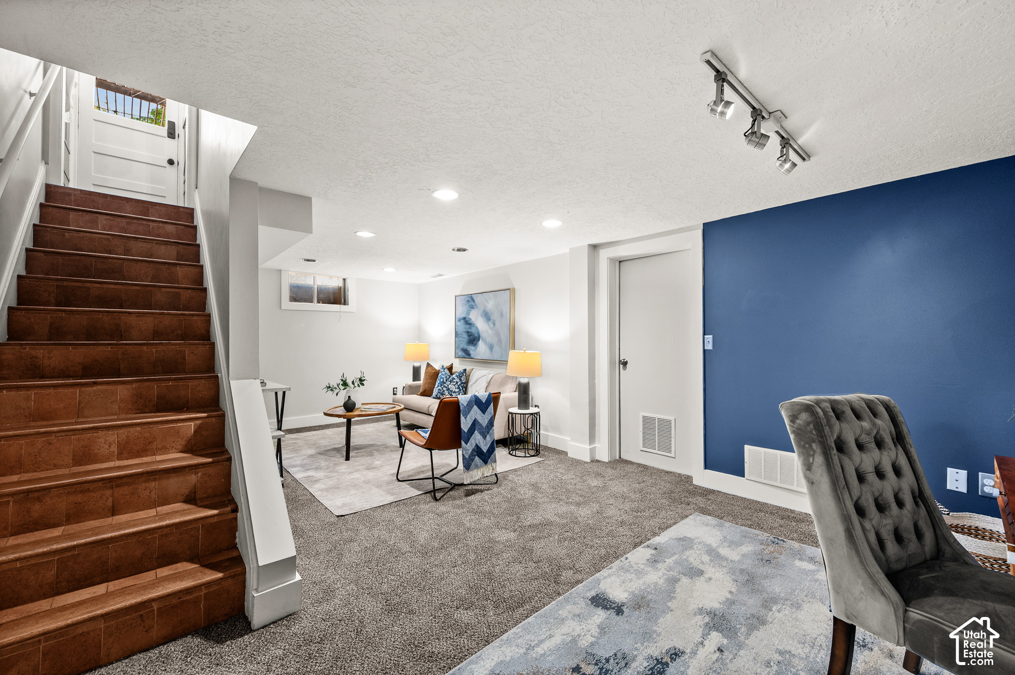 Staged basement living area with a tiled staircase and blue accent wall.