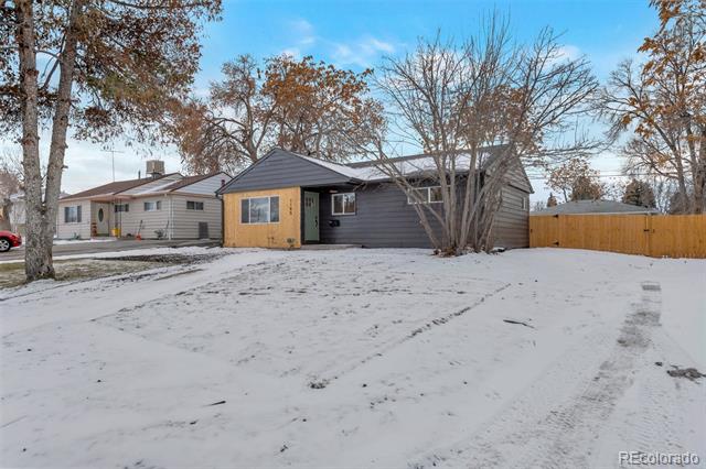 Single-story gray and mustard-yellow house with a snow-covered front yard and wooden fence.