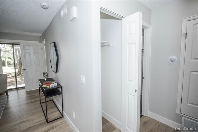 Entry hall with an open coat closet, wood-look flooring, and a narrow console table beside a sliding glass door.