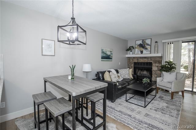 Open-plan living and dining area with a stone fireplace, black sofa, and gray dining table.