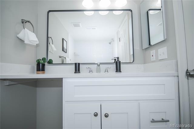 Bathroom vanity with double sinks, dark faucets, a large mirror, and a small potted plant.