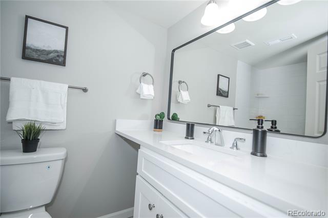 Bright bathroom with a long white vanity, double sinks, large mirror, and toilet.