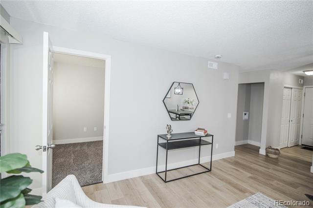 Condo living area with light wood-look floors, geometric mirror, and console table.