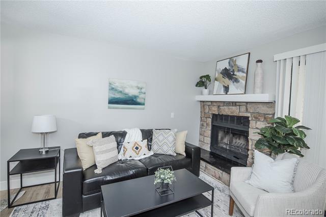 Living room with a black leather sofa, stone fireplace, and white armchair.