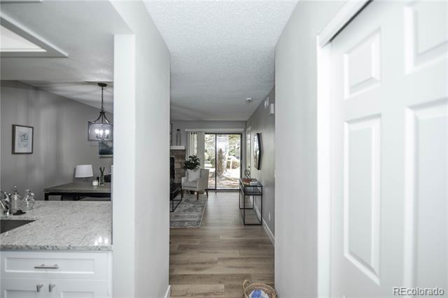 Hallway leading to a furnished living area with patio doors, beside a granite kitchen counter.