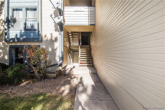 Residential building entry with a concrete walkway leading to an exterior staircase.