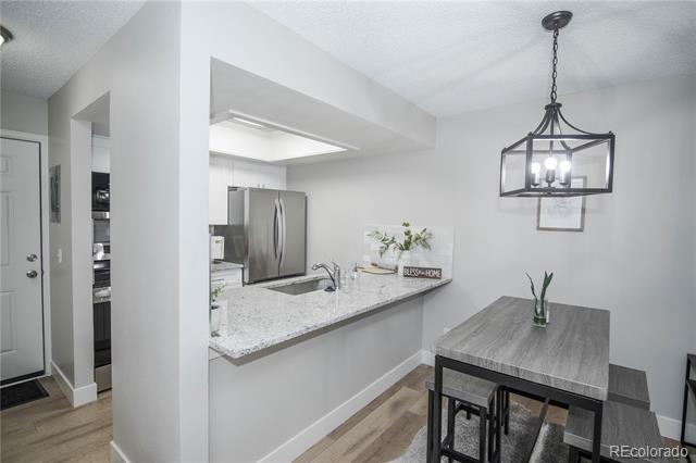 Open kitchen and dining area with a stone breakfast counter, stainless appliances, and a gray table.