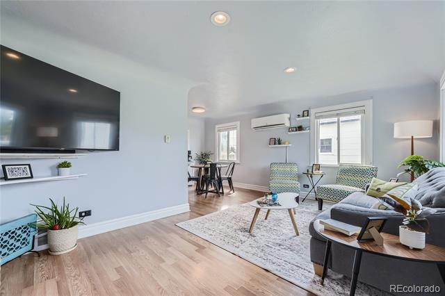 Living room with a gray sectional, patterned chairs, and a dining area beside the windows.