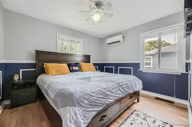 Bedroom with a dark wood bed, mustard-yellow pillows, navy lower walls, and two windows.