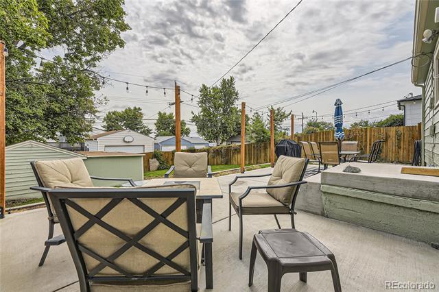 Backyard patio with cushioned chairs, a raised seating area, and a wooden fence.