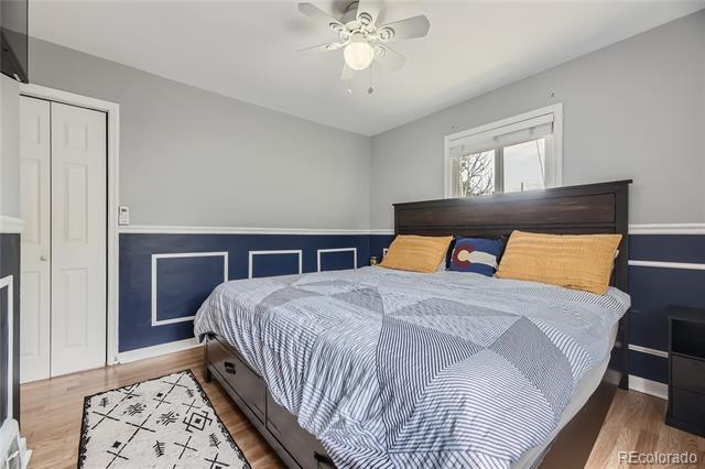 Bedroom with a dark wood bed, patterned bedding, blue wainscoting, and a ceiling fan.