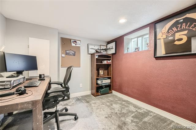 Home office with a wood desk, rolling chair, and framed number 5 jersey on a red wall.