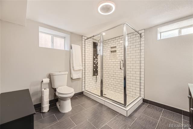 Bathroom with a glass-enclosed white subway-tile shower and dark gray floor.
