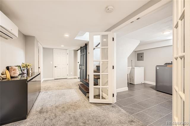 Finished basement with carpeted living area, open French door, and tiled laundry area.