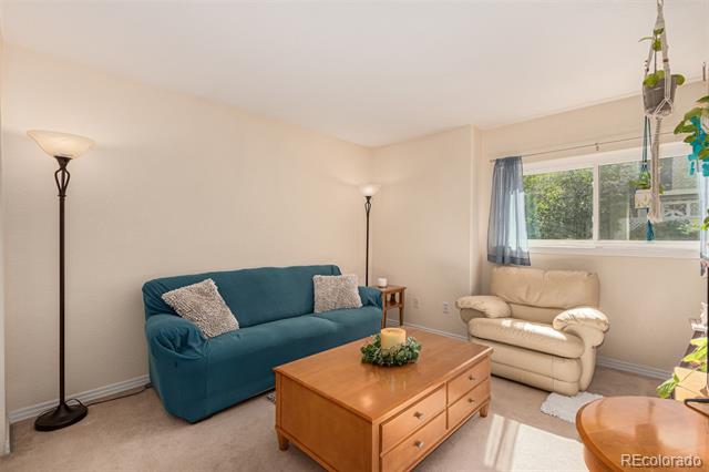 Living room with a teal sofa, cream loveseat, wooden coffee table, and window with blue curtains.