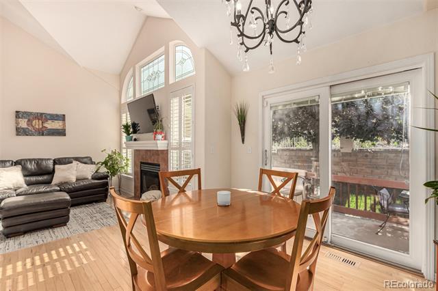 Dining area with a round wood table beside a living room, fireplace, and patio doors.