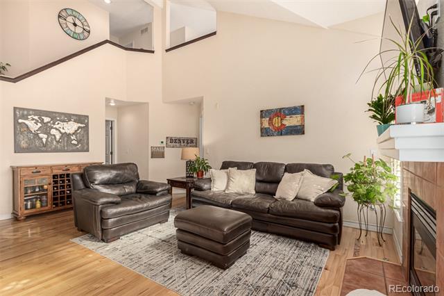 Two-story living room with leather seating, hardwood floors, a patterned rug, and a fireplace.