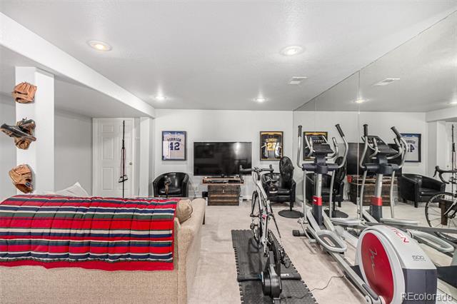 Basement home gym with treadmills, stationary bikes, a mirrored wall, and a sofa.