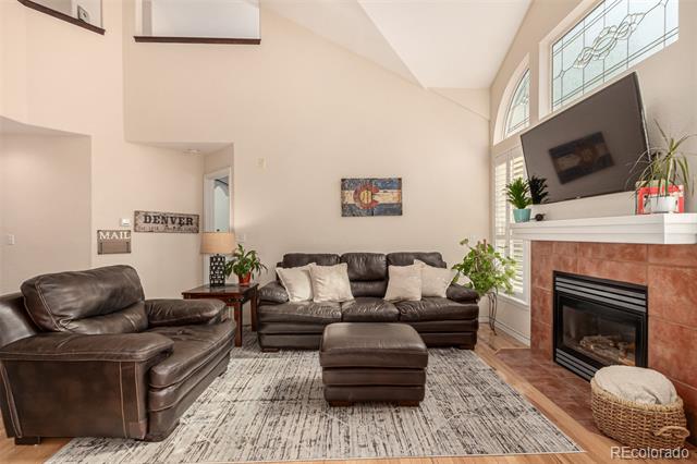 Living room with dark leather sofas, vaulted ceiling, fireplace, and wall-mounted television.
