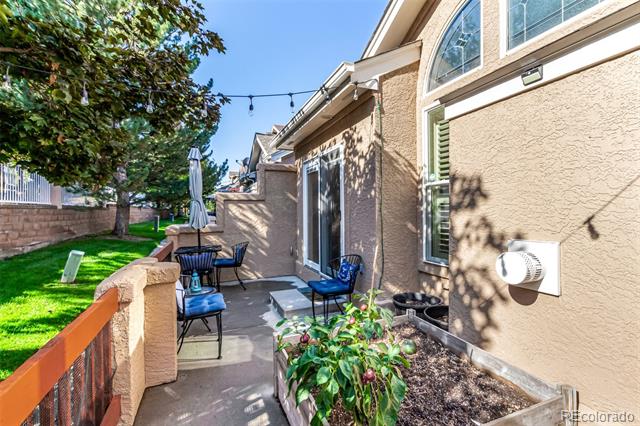 Private patio beside a tan stucco home, furnished with a small dining set and umbrella.