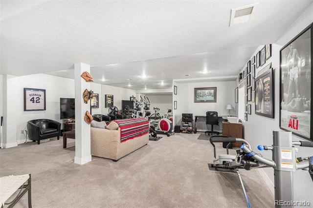Finished basement exercise room with workout equipment, a sofa, and framed sports memorabilia.