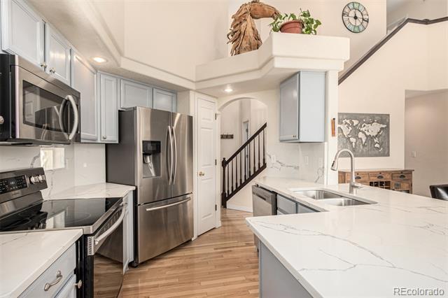 Kitchen with stainless steel appliances, white countertops, and a large island with a sink.
