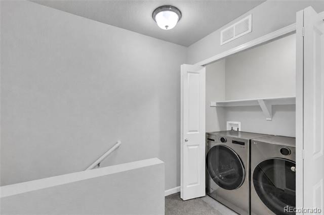 Laundry area with front-loading washer and dryer beside a stair landing.