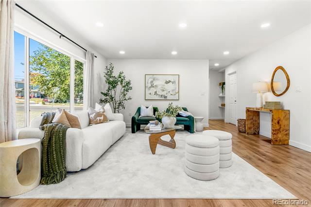 Staged living room with emerald accent chairs, a sculptural coffee table, and large windows.