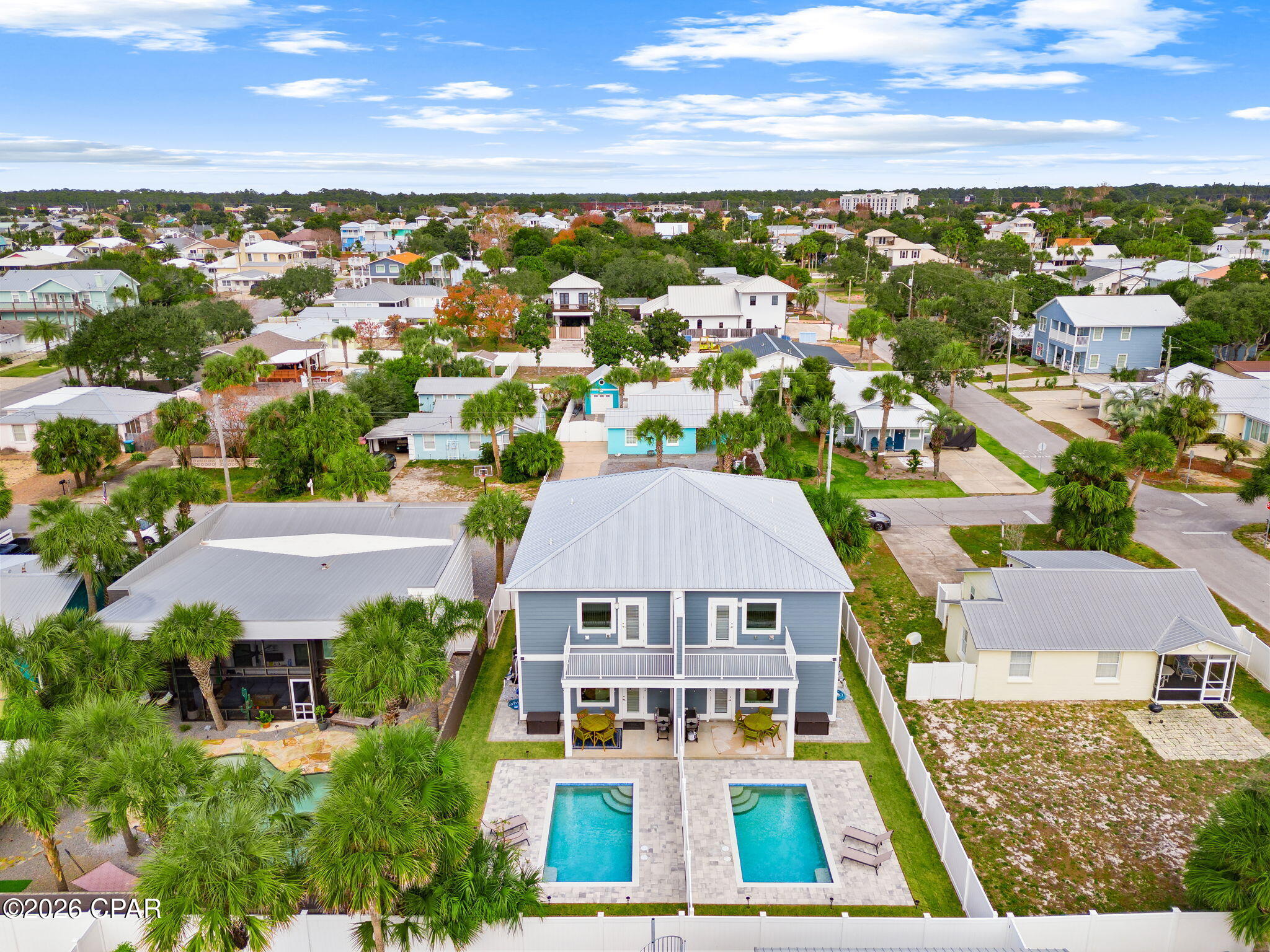 Blue two-story duplex with two separate swimming pools, viewed from above.