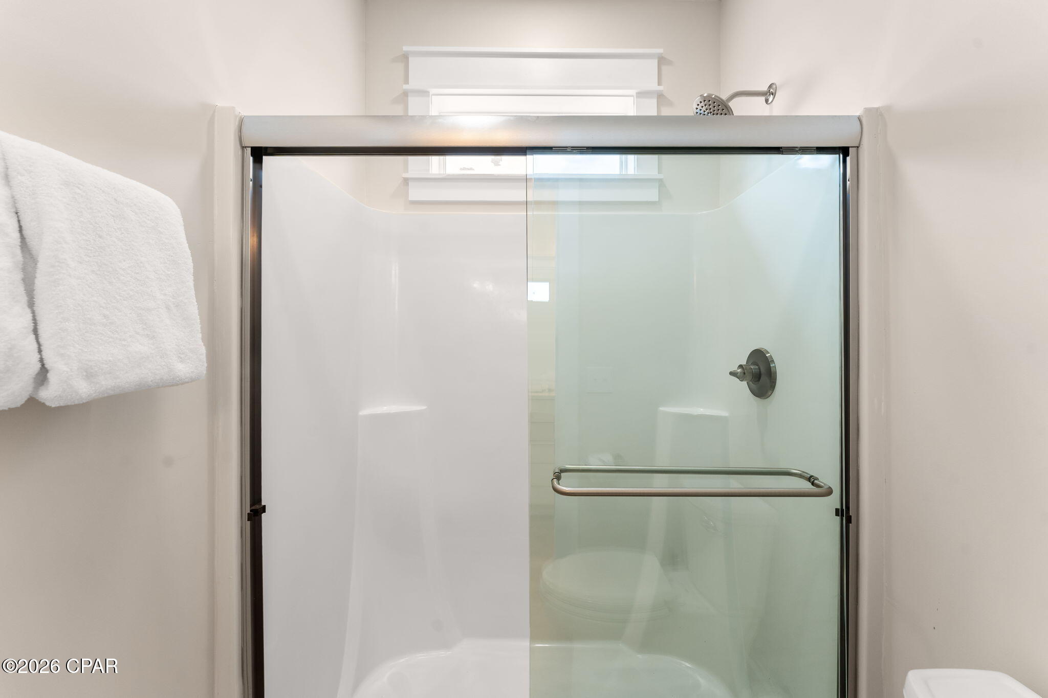 Glass-enclosed bathroom shower with chrome fixtures and a built-in seat.