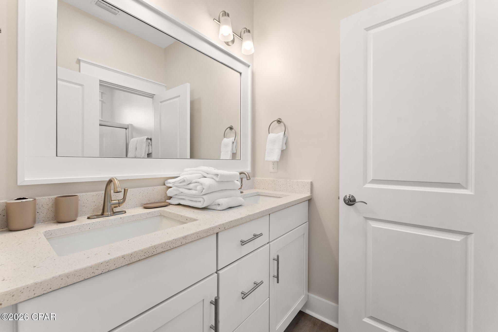 Bathroom vanity with a large mirror, speckled countertop, brushed metal faucet, and folded white towels.