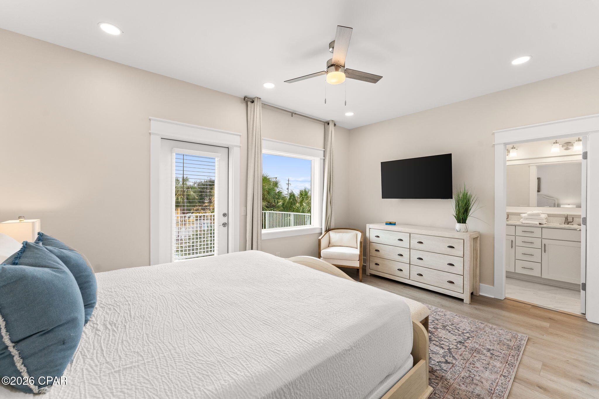 Furnished bedroom with a large white bed, blue pillows, and an ensuite bathroom.
