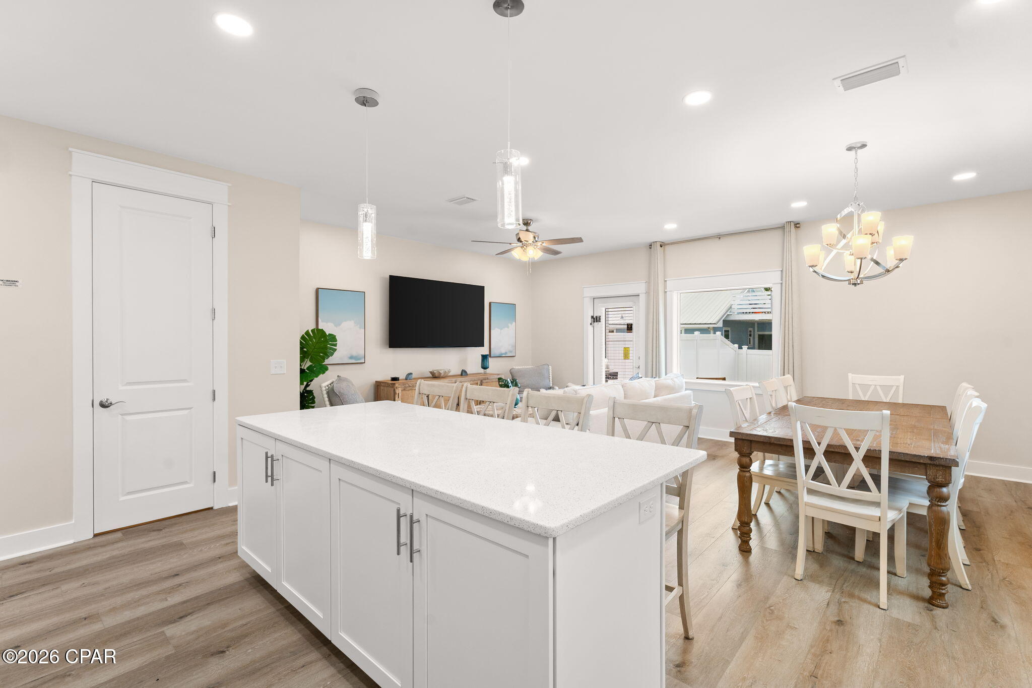 Open-plan kitchen and dining area with a large white island and wood dining table.