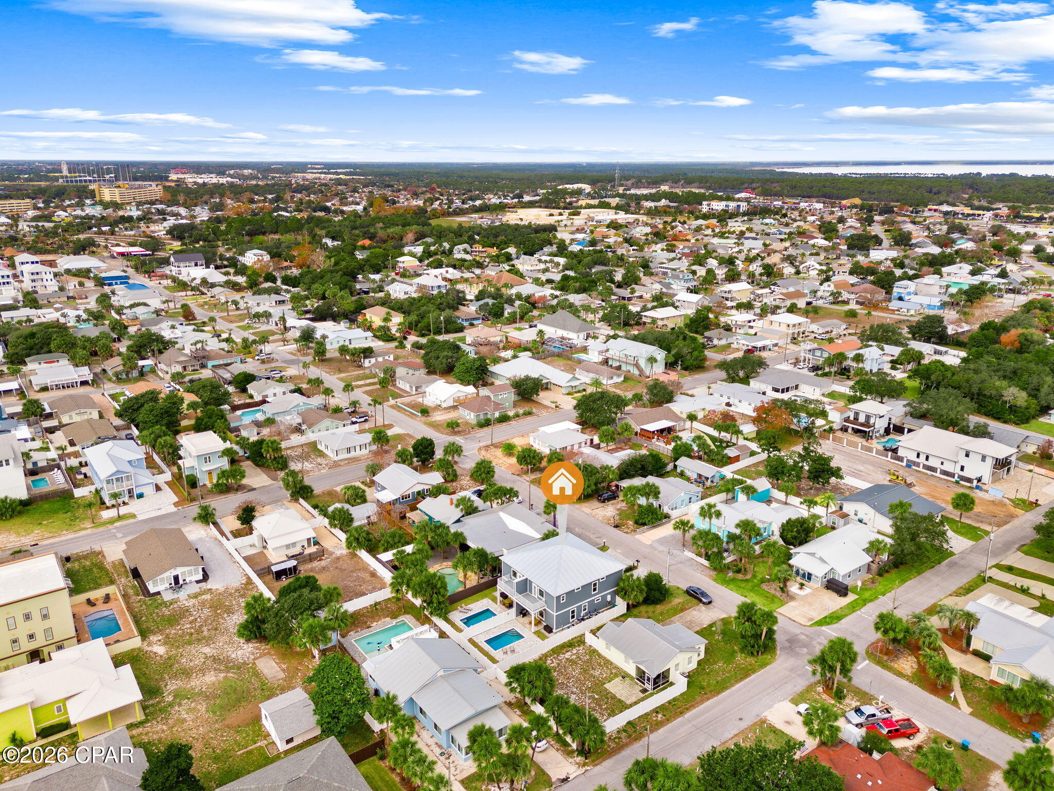 Aerial view of a residential neighborhood, with an orange house marker and water on the distant horizon.