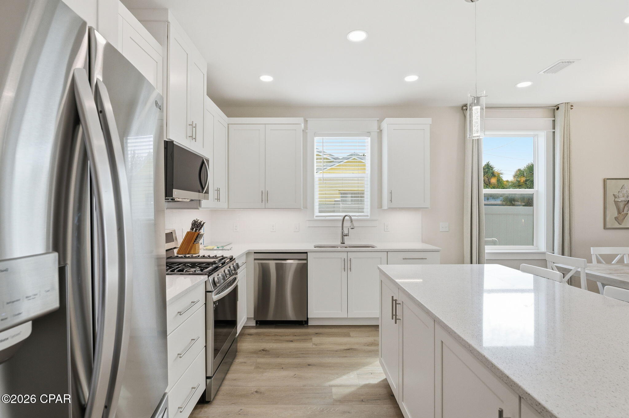Modern white kitchen with a large quartz island and stainless steel appliances