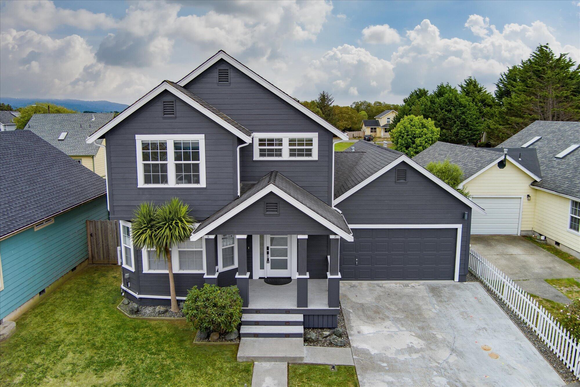 Two-story charcoal-gray house with white trim, covered porch, and attached garage, viewed from above.