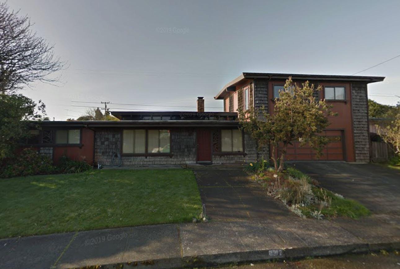 Two-story house with gray shingle cladding, red-brown siding, and a broad driveway.